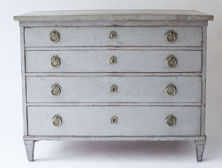 A Swedish grey painted Gustavian period chest of drawers with a drop front revealing a writing surface and a series of drawers with original knobs. The unusual stone top is from the Island of Gotland. The brasses are original and the secondary grey