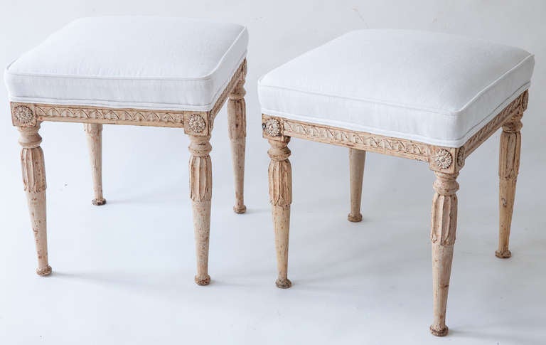 A lovely pair of Swedish Gustavian period footstools,in original paint surface. The rounded legs have beautifully carved details and flower medallions at each corner. The stools have been newly upholstered in a vintage French linen fabric. Sweden