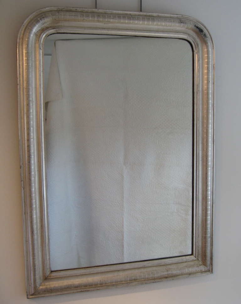 A Louis Philippe silver gilt mirror with a pattern of geometric design on the frame.