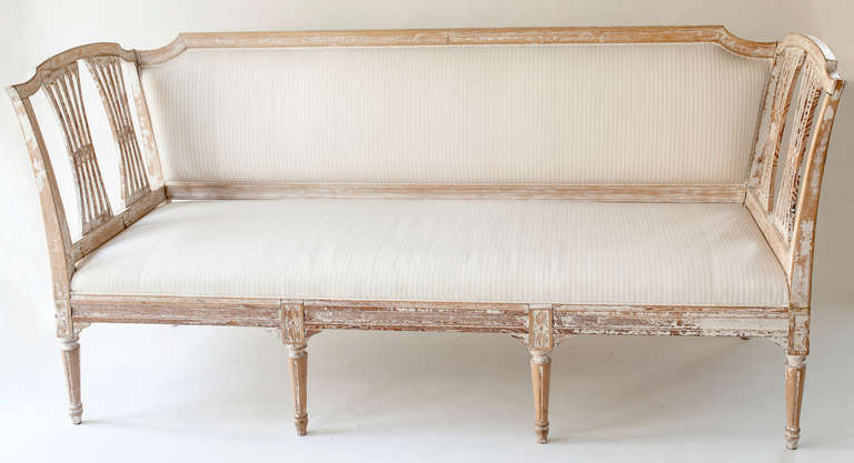 An elegant Swedish Gustavian period bench with open sides in a fan shape. This piece has been carefully dry scraped to reveal traces of the original white paint. It has been completely reupholstered in a cream and pale peach linen with a