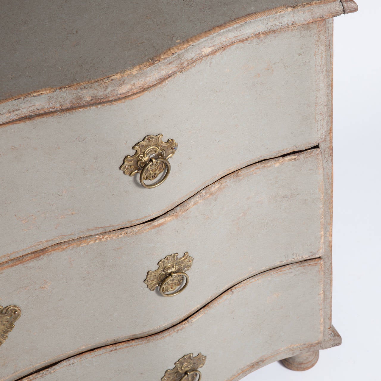 This lovely Swedish three-drawer serpentine chest from the Baroque period has a gently curved front ending in pad feet. It retains all of the original and very elegant hardware from the period. The top drawer is divided. It dates to 1760. The pale