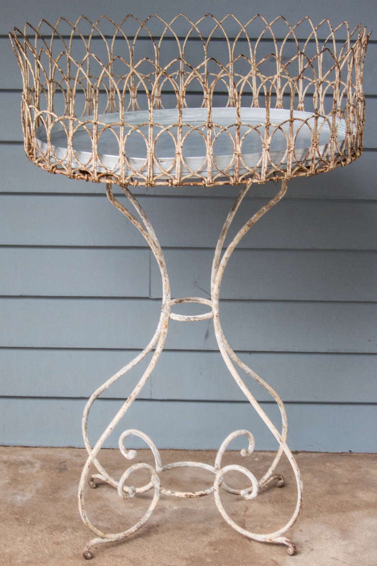 An elaborate Victorian period jardiniere with traces of old white paint and an elegant scrolled base.  the two tier wirework top is unusual. New zinc liner. 