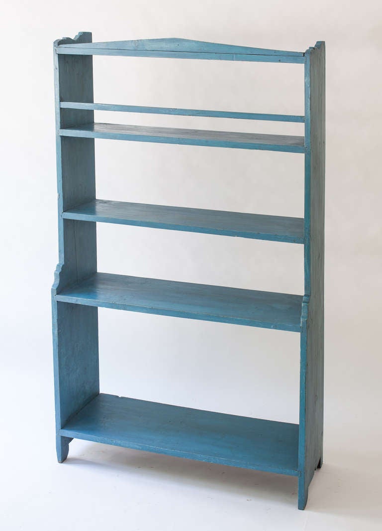 An American five tier storage shelf in the original blue paint with some restoration. There are decorative details on the top and side panels typical of the period. The great blue paint color is what makes this piece unique. It dates to the late