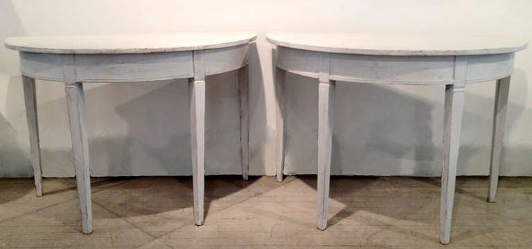 A pair of Swedish late 19th century demi-lune tables in old white/grey paint with later paint on the top. A great pair that will seat six. circa 1880.