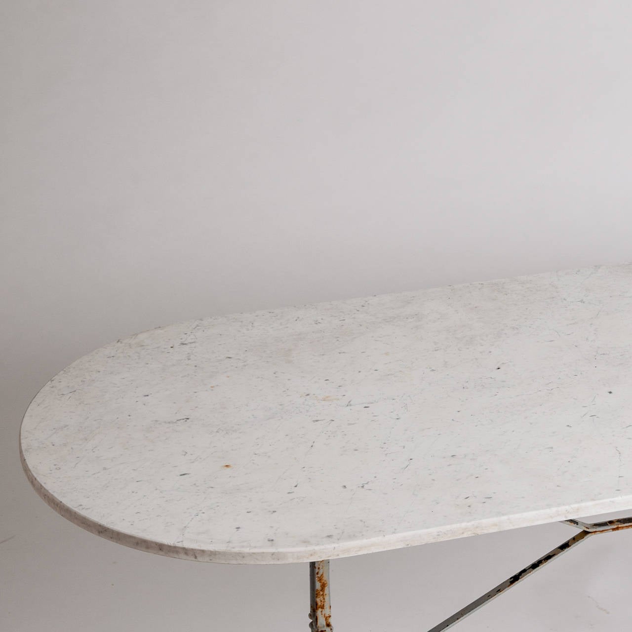 This French bistro table with an elegant oval marble top is a perfect size for dining and can easily sit six people. The antique cast iron base is painted a pale blue/grey and has nice pad feet that lend stability. The marble is in good condition.