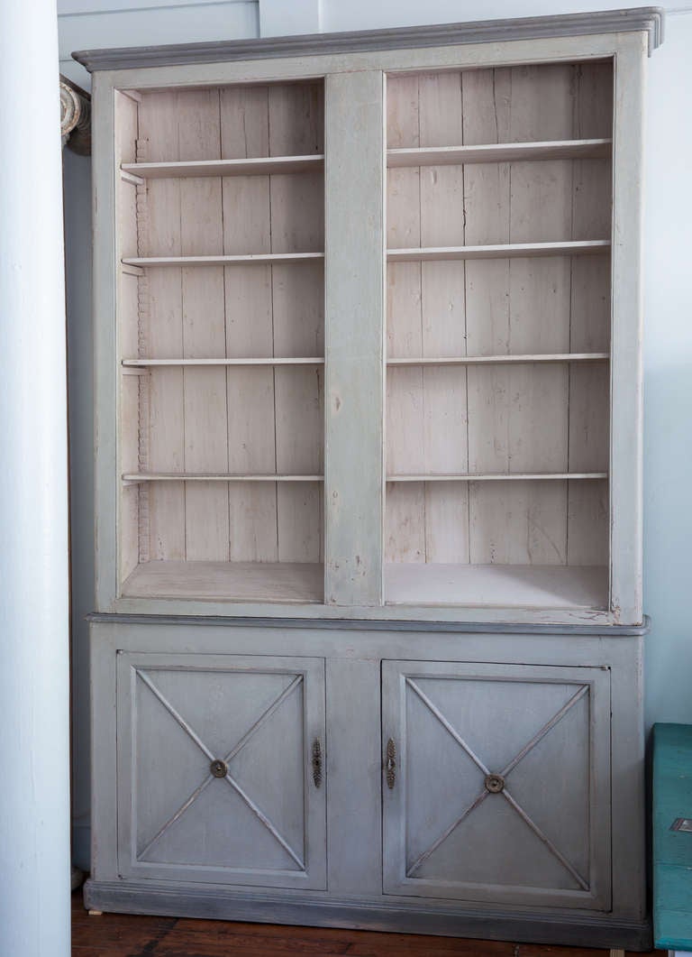 A French  library in old grey paint with four open adjustable shelves and a bottom shelf designed to display books. The  bottom doors open to two additional shelves for storage. The old grey paint has a wonderful patina and the doors have elegant