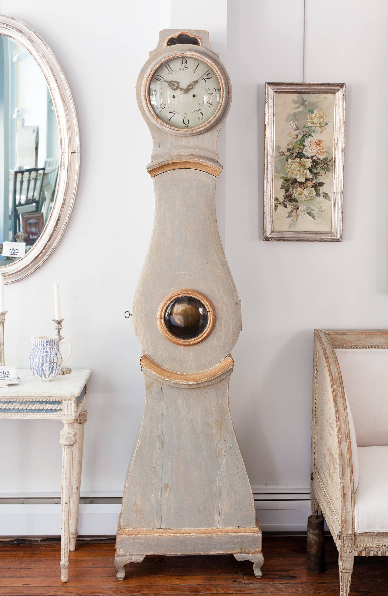 An elegant Swedish Rococo period clock in the original very pale green paint surface with touches of gold remaining on the face and bevel and standing on curved feet typical of the period. The clock has a side window revealing the works and a large