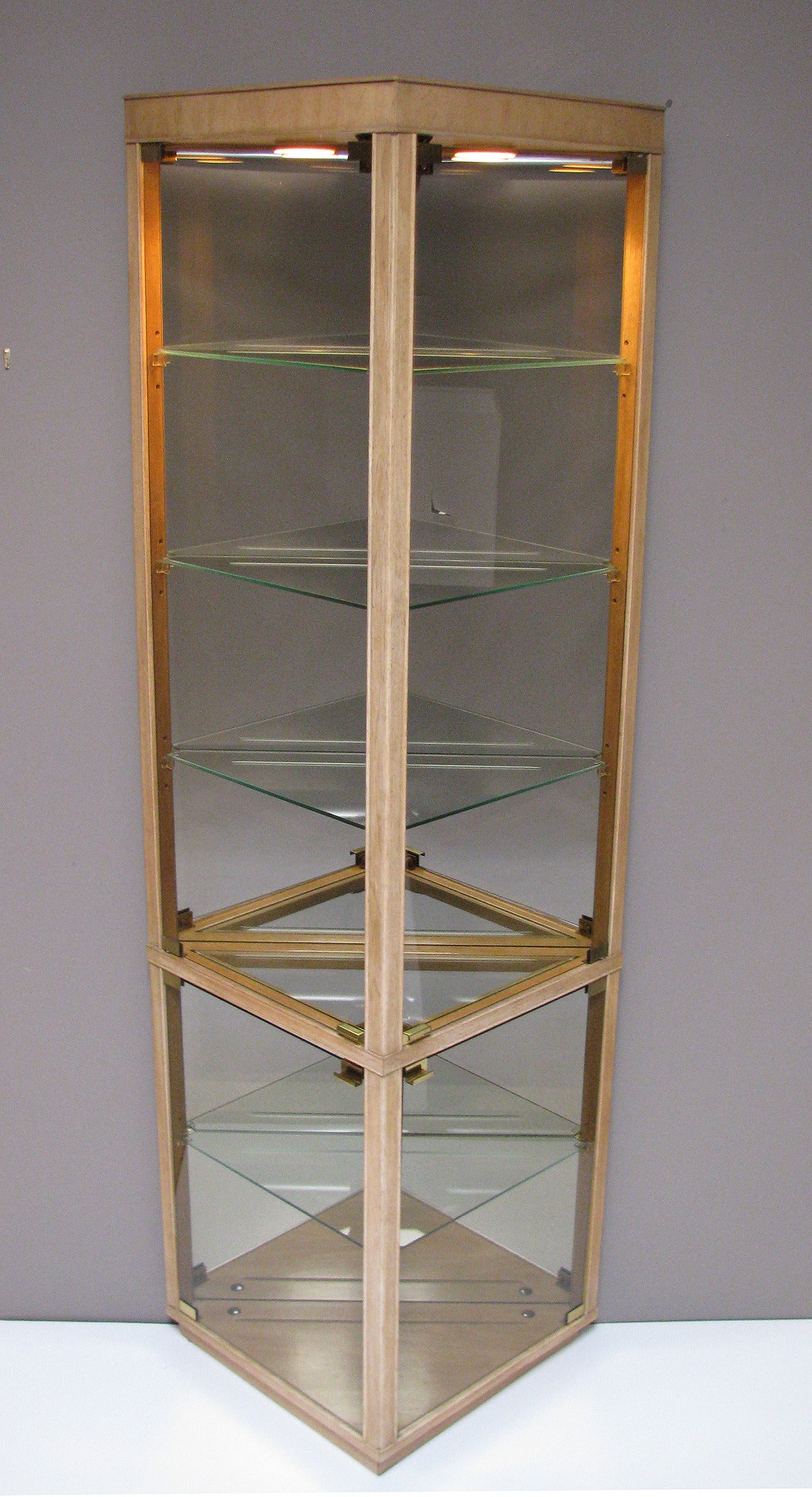 Three triangular-shaped vitrines by Drexel Heritage, with bronze-tint glass doors, illuminated interior. Each cabinet is mirrored-backed and features four adjustable glass shelves, plus one stationary center glass shelf. Drexel Heritage, preface