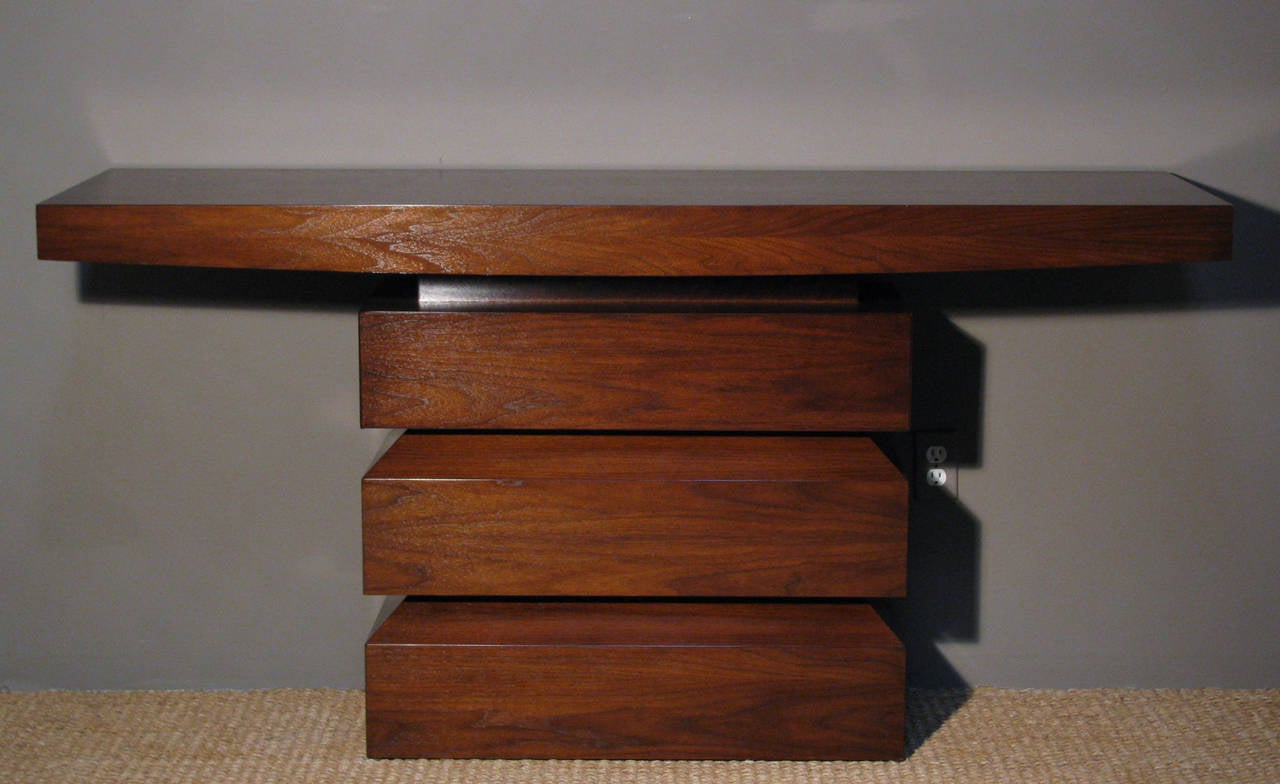 A solid walnut console 'Wedge' by Peter Alexander Furniture featuring a custom hidden drawer. We have one available in-stock for quick ship as shown.