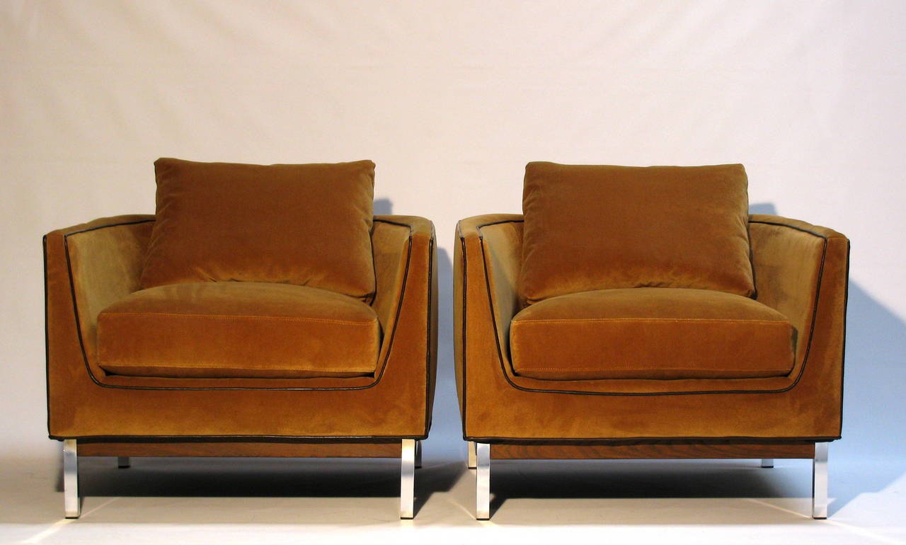 A stunning pair of lounge cube chairs by Selig. These stylish low-profile chairs feature a down-wrapped seat cushion, a loose feather down back pillow; upholstery is a caramel velvet by J.B. Martin, with dark brown leather trim. The base is walnut