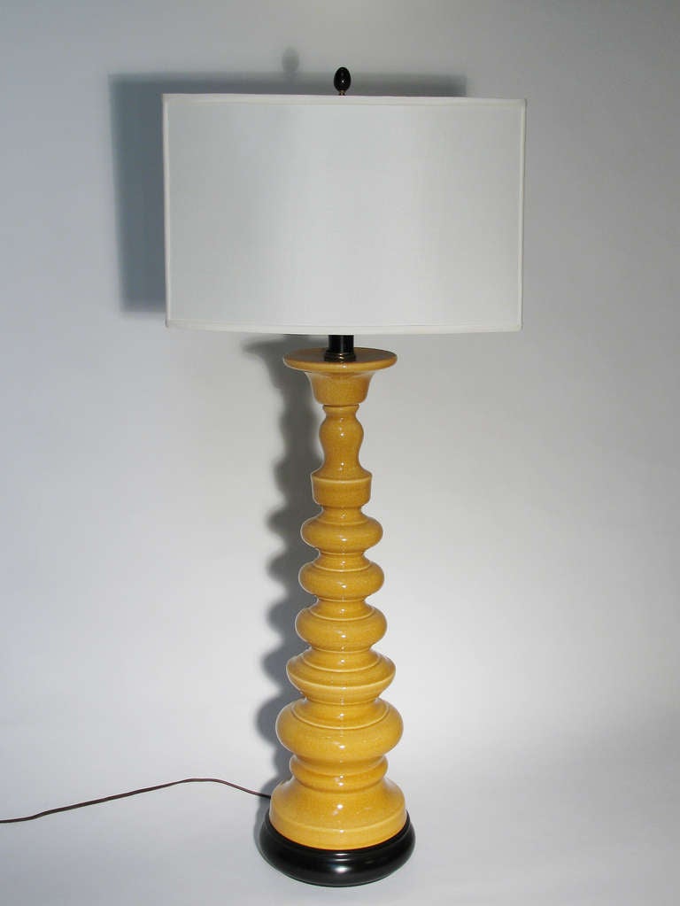 A sculptural pair of large scale table lamps in a yellow ochre color, crackle glazed ceramic mounted on ebonized wood bases. Circa 1950-1960. Height measurements including shade is 41