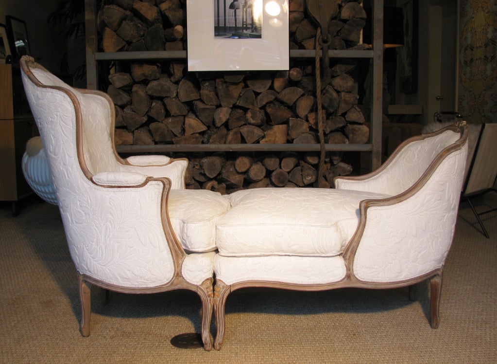 A stunning two part lounge chair, Duchesse en Brisee, comprised of two 'gondola type' chairs of different depth and height,<br />
combined seats end to end with curved backs. Upholstery is an ivory raised leaf pattern, and the beech wood frame has
