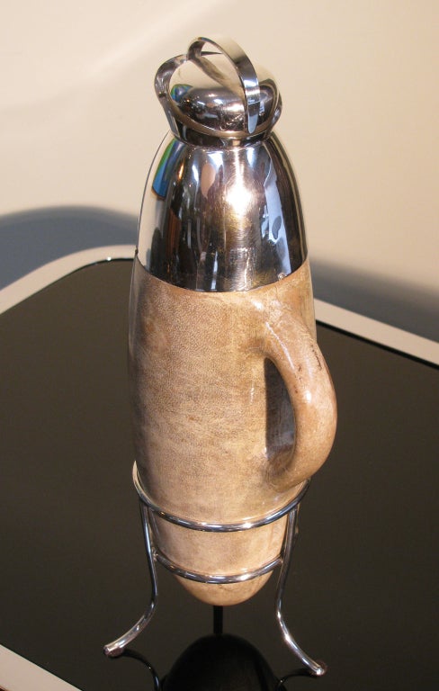 A rare lacquered goatskin carafe or decanter by Aldo Tura. Goatskin is a rich taupe color with silver plated spout, tripod stand, and stopper with cork bottom. Interior is silver glass lined. 