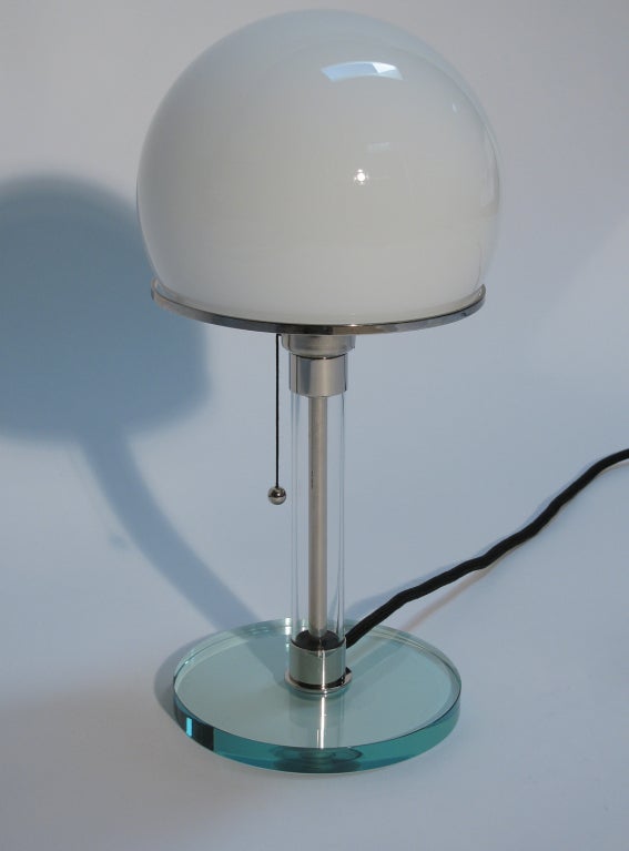 This handcrafted table lamp, circa 1970s designed by Wilhelm Wagenfeld for Tecnolumen, Germany. The original design was conceived in 1924, is often named the Bauhaus lamp. The materials used consist of; nickel-plated metal parts, clear glass, opaque
