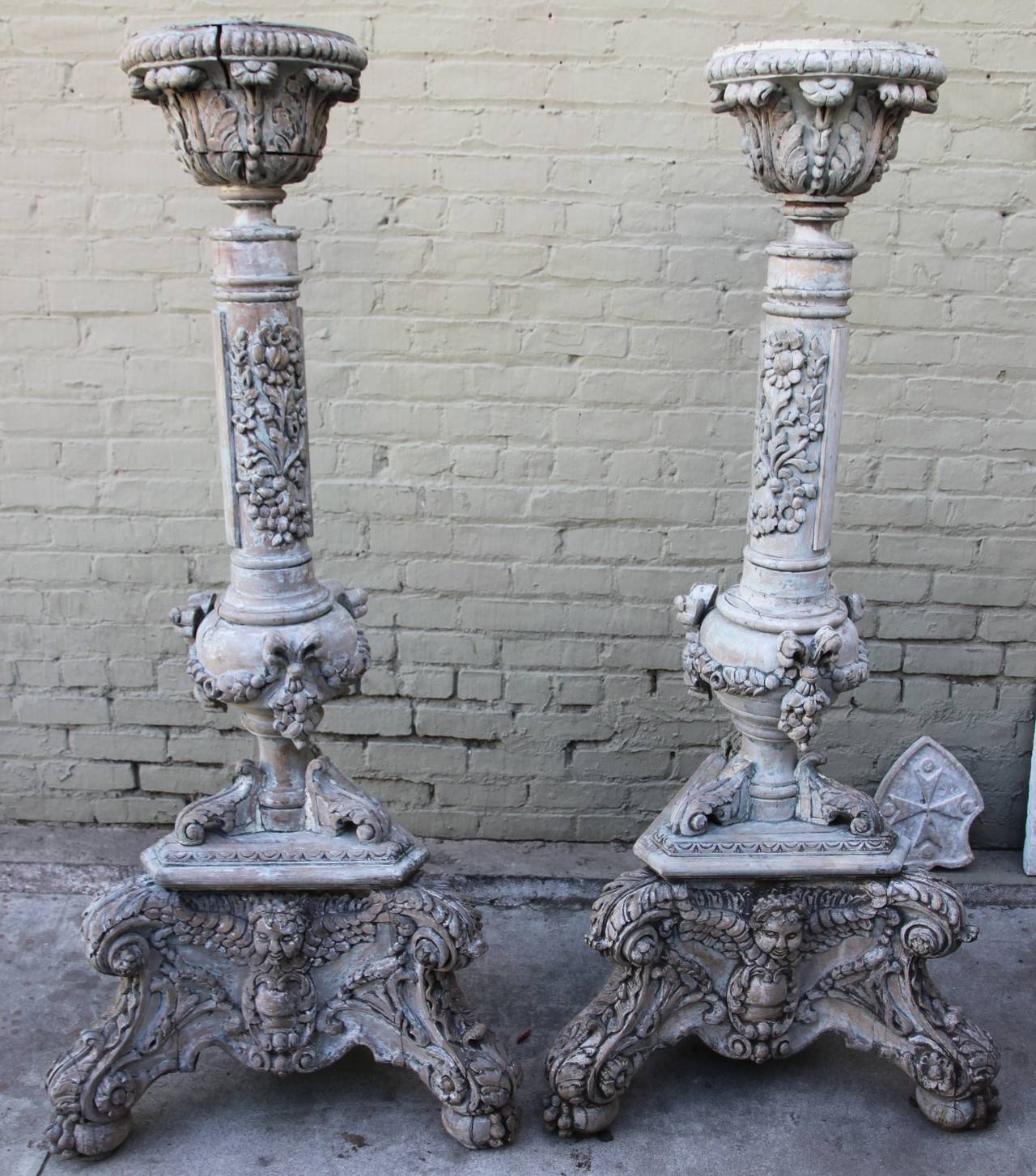 Pair of heavily carved Italian painted torchieres depicting cherubs, acanthus leaves and garlands of flowers throughout.