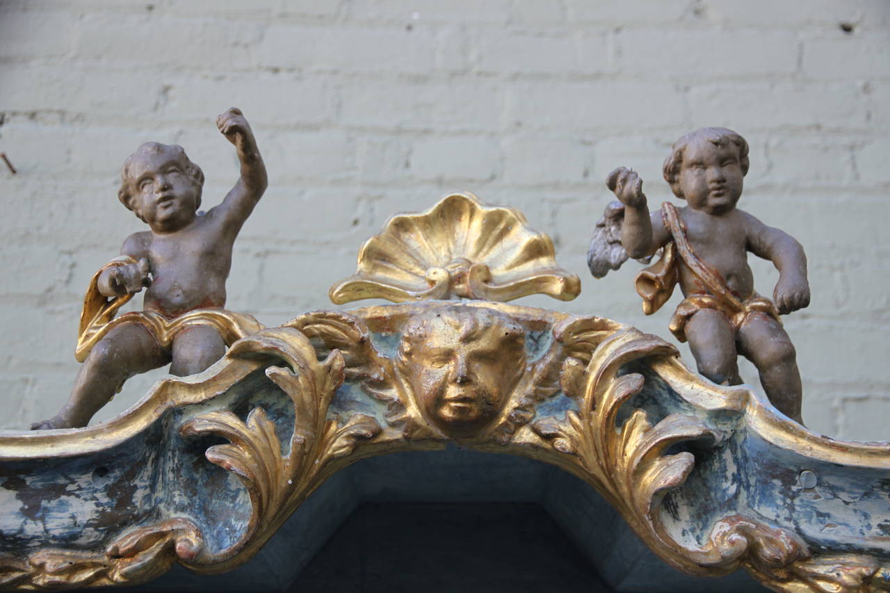 Painted & parcel gilt Italian bookcase comprised of 19th century elements.  Four cherub finials.  Two adjustable shelves.