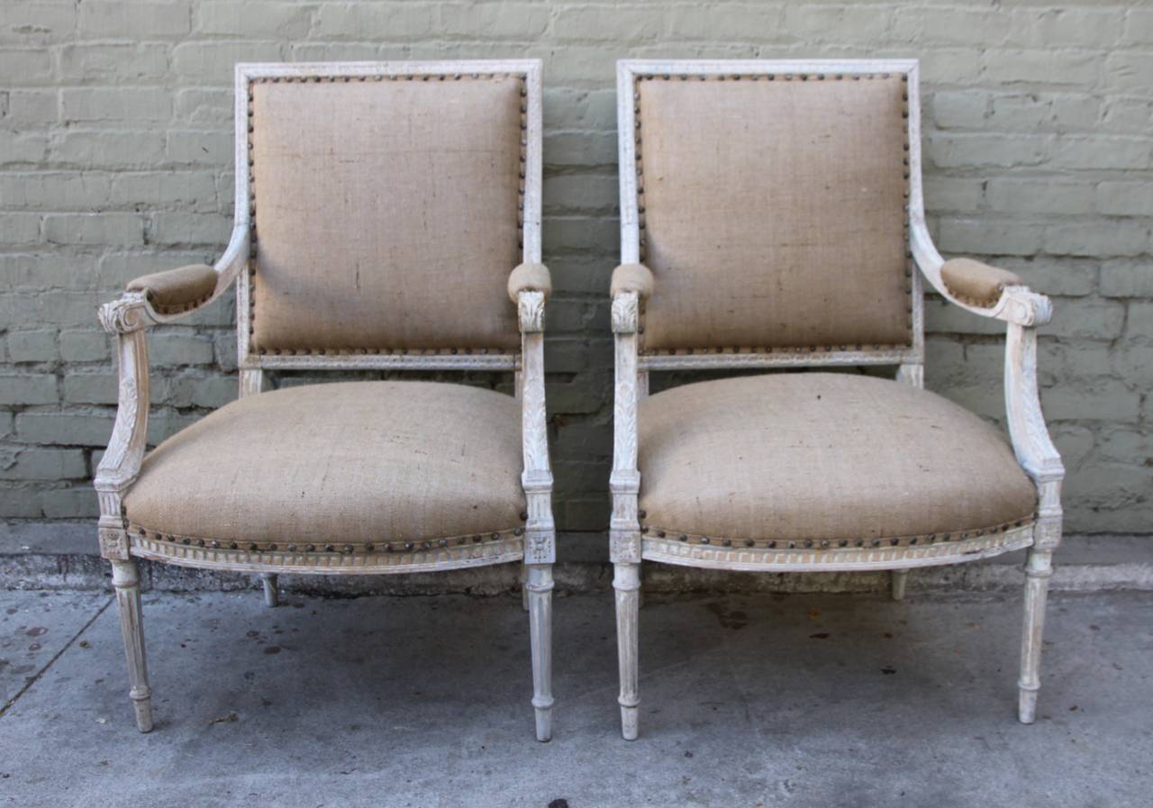 Pair of Louis XVI style painted armchairs newly upholstered in burlap fabric with spaced nailhead trim detail.