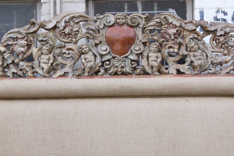 Newly upholstered. Carved painted architectural piece incorporated into a king size burlap upholstered headboard with nailhead trim detail.   You can personalize this piece by adding your monogram in the center cartouche.