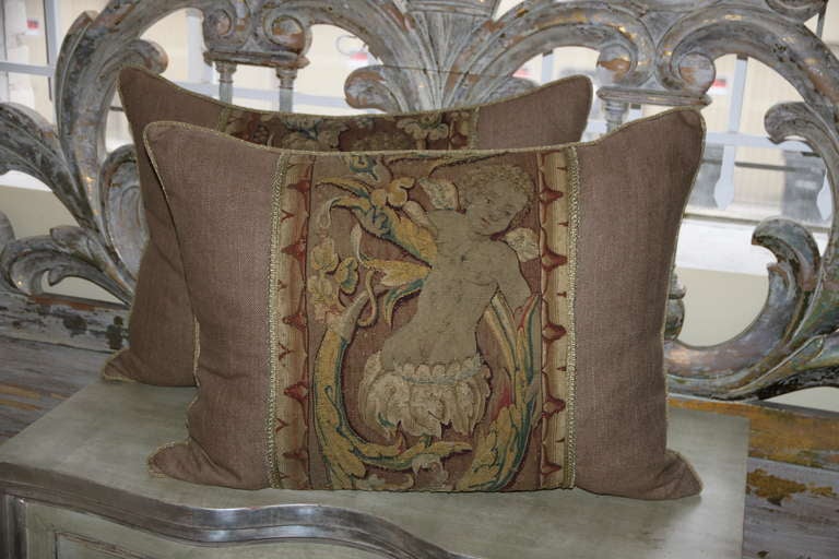 Pair of French 18th century cherub tapestry pillows with gold cord detail, linen background and down inserts.