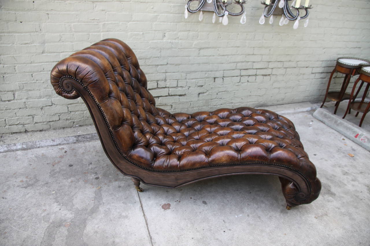 Continental wood and leather tufted chaise longue with nailhead trim detail and casters.
