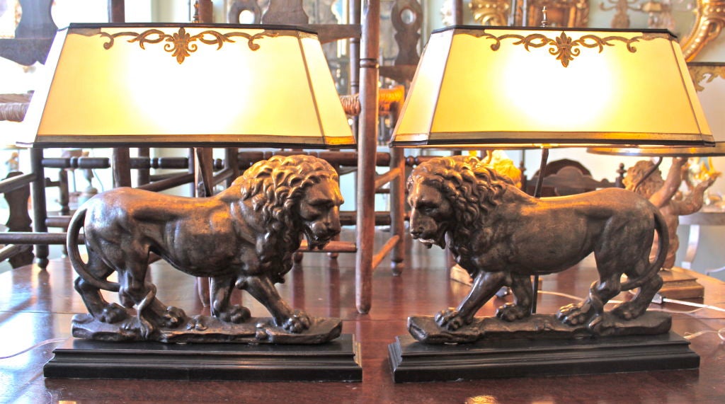 Pair of rare monumental lions French mounted on wood based and crowned with hand painted parchment shades.  Beautifully cast, great patina.  These lamps will make a grand statement in any decor!