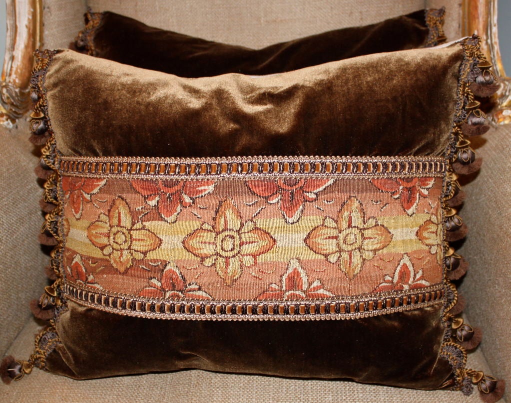 Pair of unique tapestry pillows in rust and yellow on chocolate brown silk velvet with wood tassel trim in the same chocolate coloration. The backs are done in a light colored linen.
