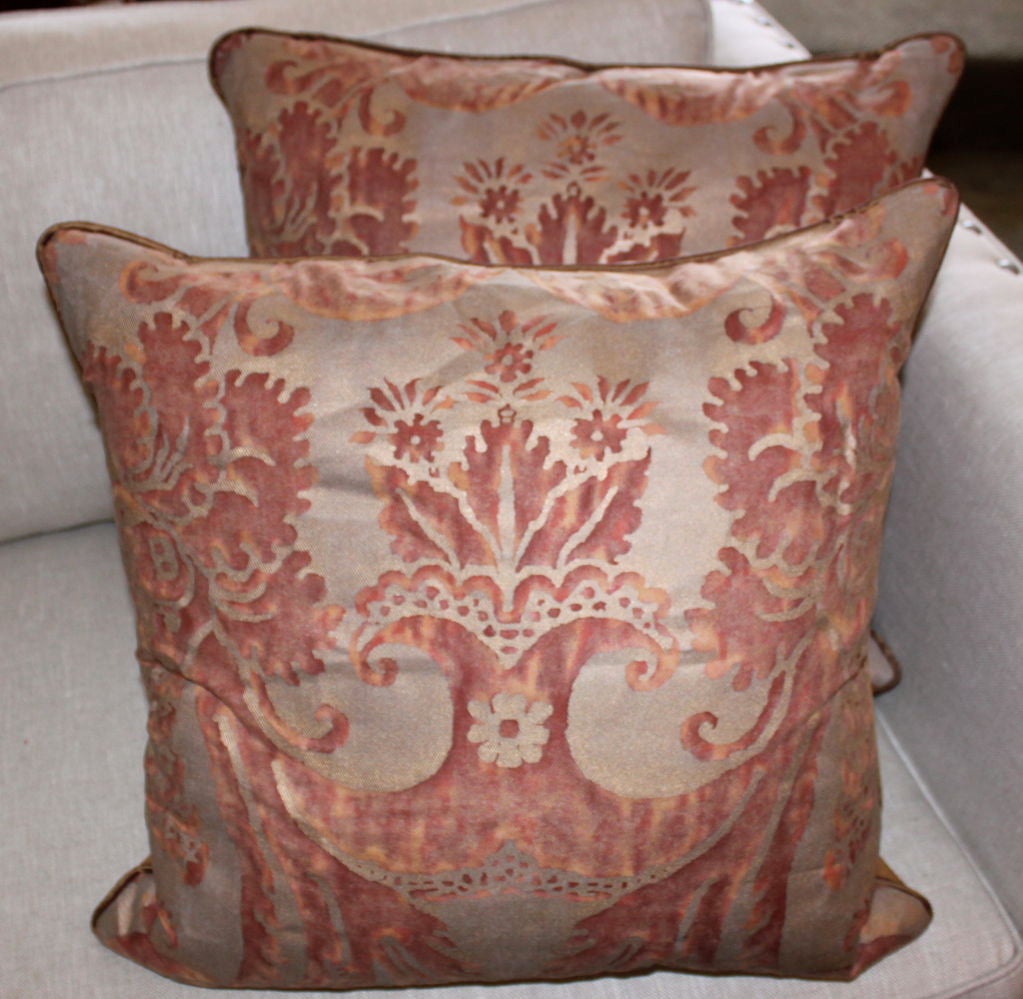 Pair of vintage Authentic Fortuny pillows. The colors are rosy apricot printed on a silvery gold background.  The backs are a golden silk.  Down filled inserts.