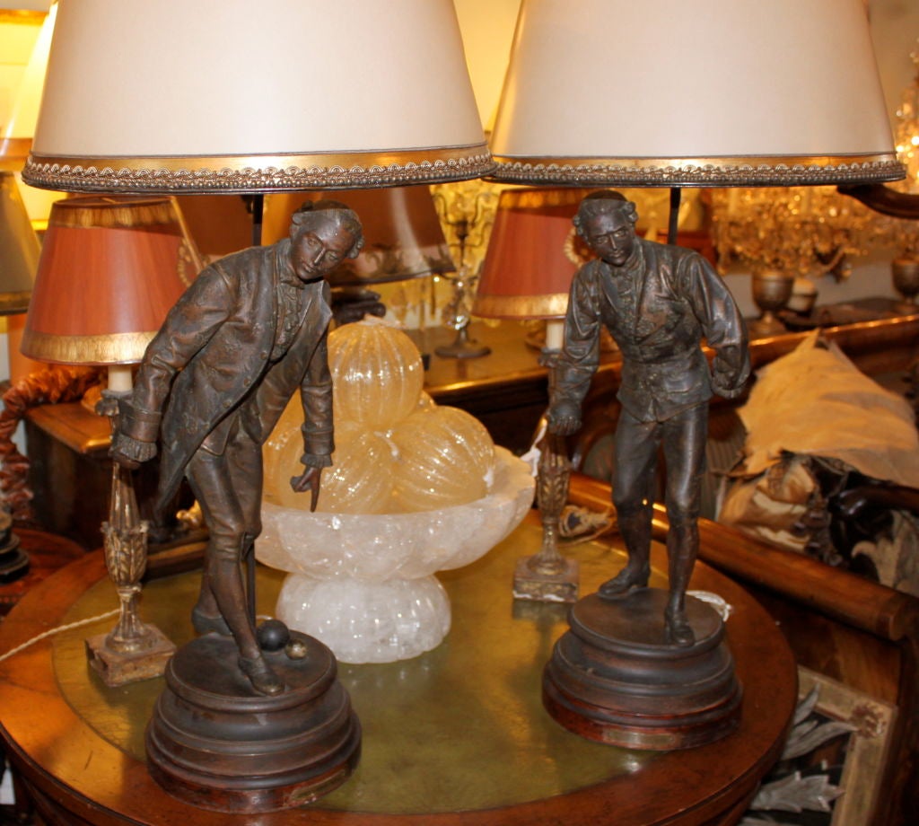 Pair of Monumental French Figural lamps made from spelter-like metal in a bronze finish.  The lamps are crowned with hand painted parchment shades.  The statues are marked with a brass plaque 