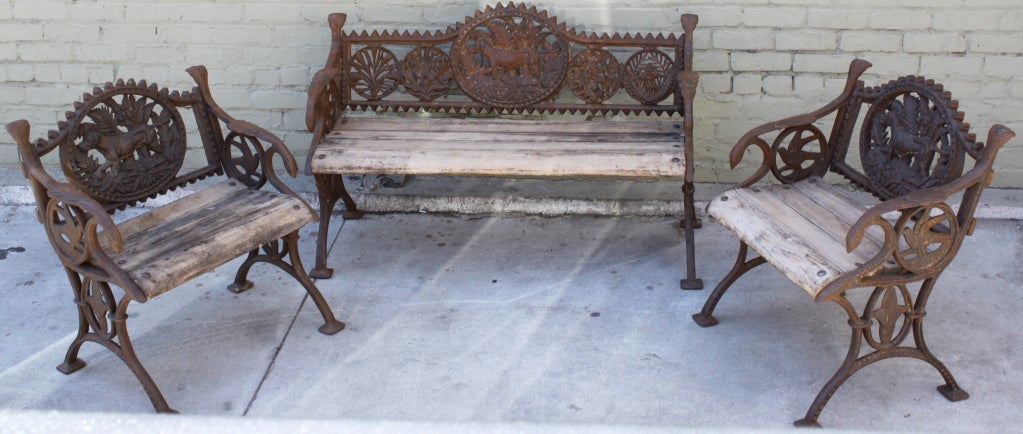 Set of one bench and two armchairs fabricated in wrought iron with wood seats.  Notice the details of the dogs, birds, foliage, and other design motifs.

Size of Bench: 49