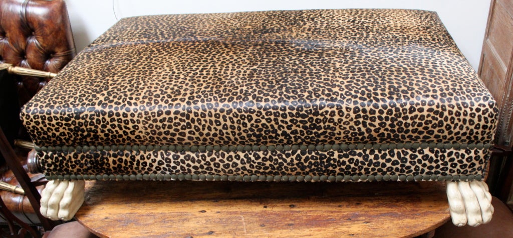 Faux leopard upholstered ottoman/bench with large nail head trim detail and carved lion paw feet.