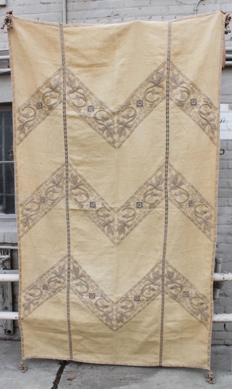 Embroidered linen textile with embroidered tassels at corners.