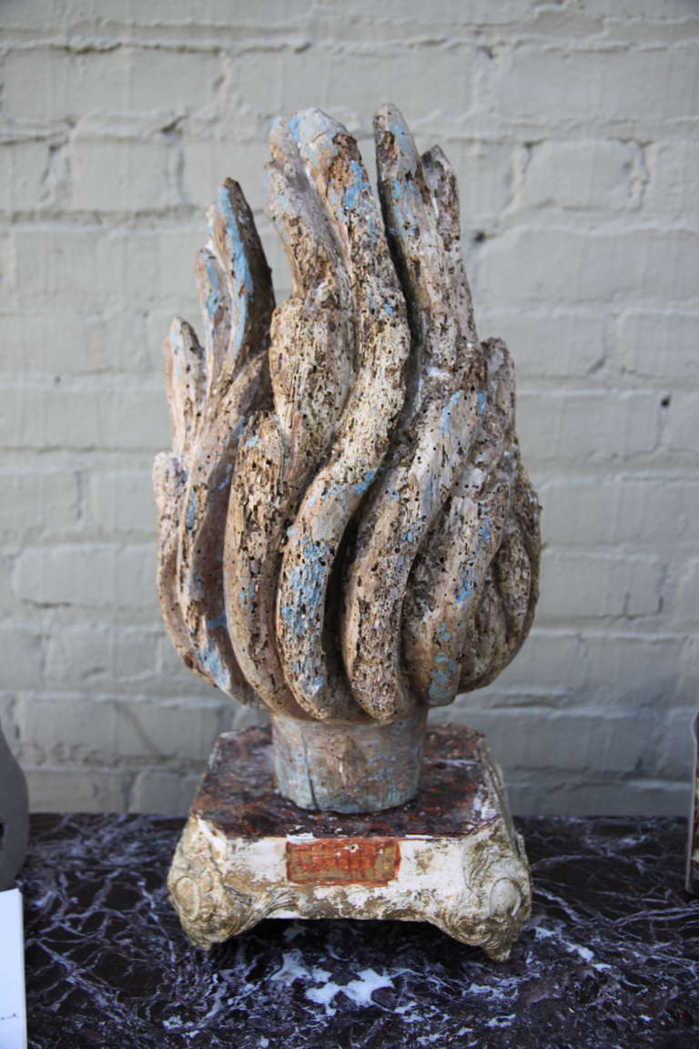 18th century carved wood flame with blue remnants of paint throughout.  The flame stands on a wood base.