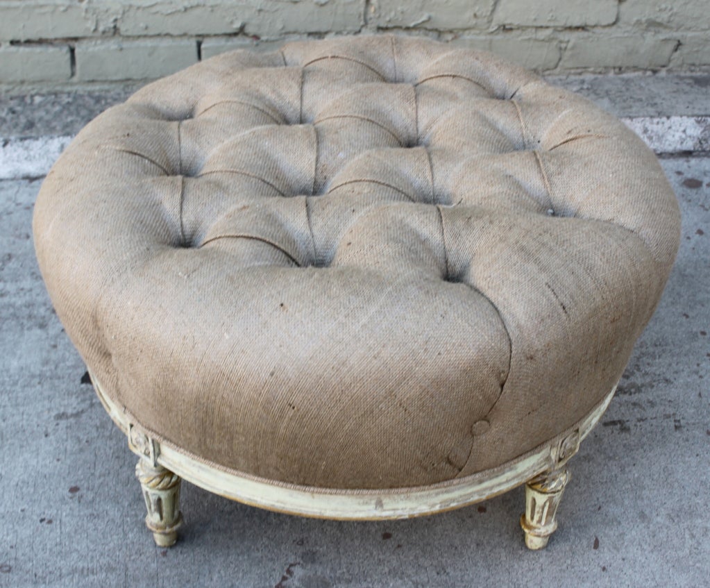 Italian carved painted ottoman upholstered in burlap with self welt cording.