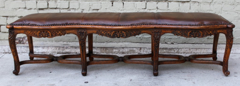 Eight legged French leather upholstered bench with nailhead trim detail.