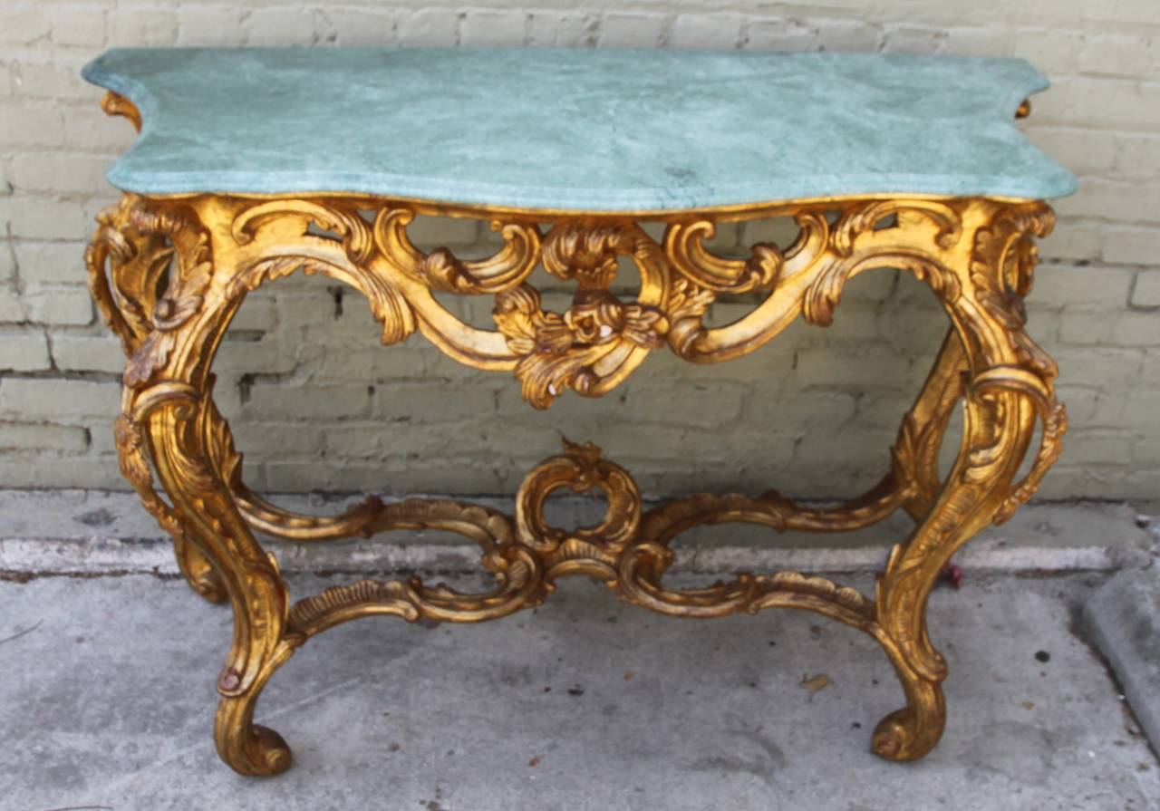 French giltwood 22-karat gold leaf console with soft green marble top standing on four cabriole legs that meet in the center by a bottom stretcher and center finial.