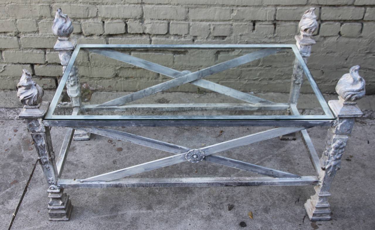 English iron coffee table made with four 19th century flamed finials. Zinc colored patina. Glass top.
