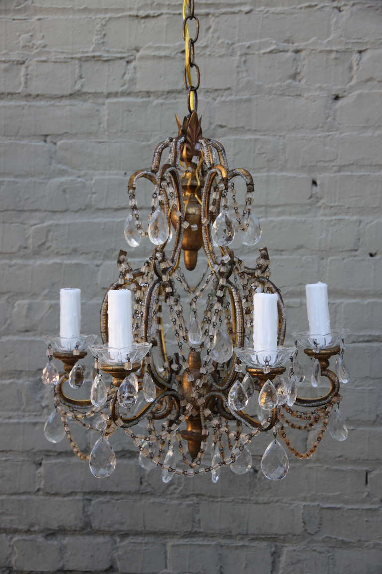 Six light Italian macaroni beaded chandelier with giltwood bobeches/finials and almond shaped crystals. Beaded arms. Gilt metal frame. Cream wax candle covers.  Newly wired and ready to install with chain and canopy.