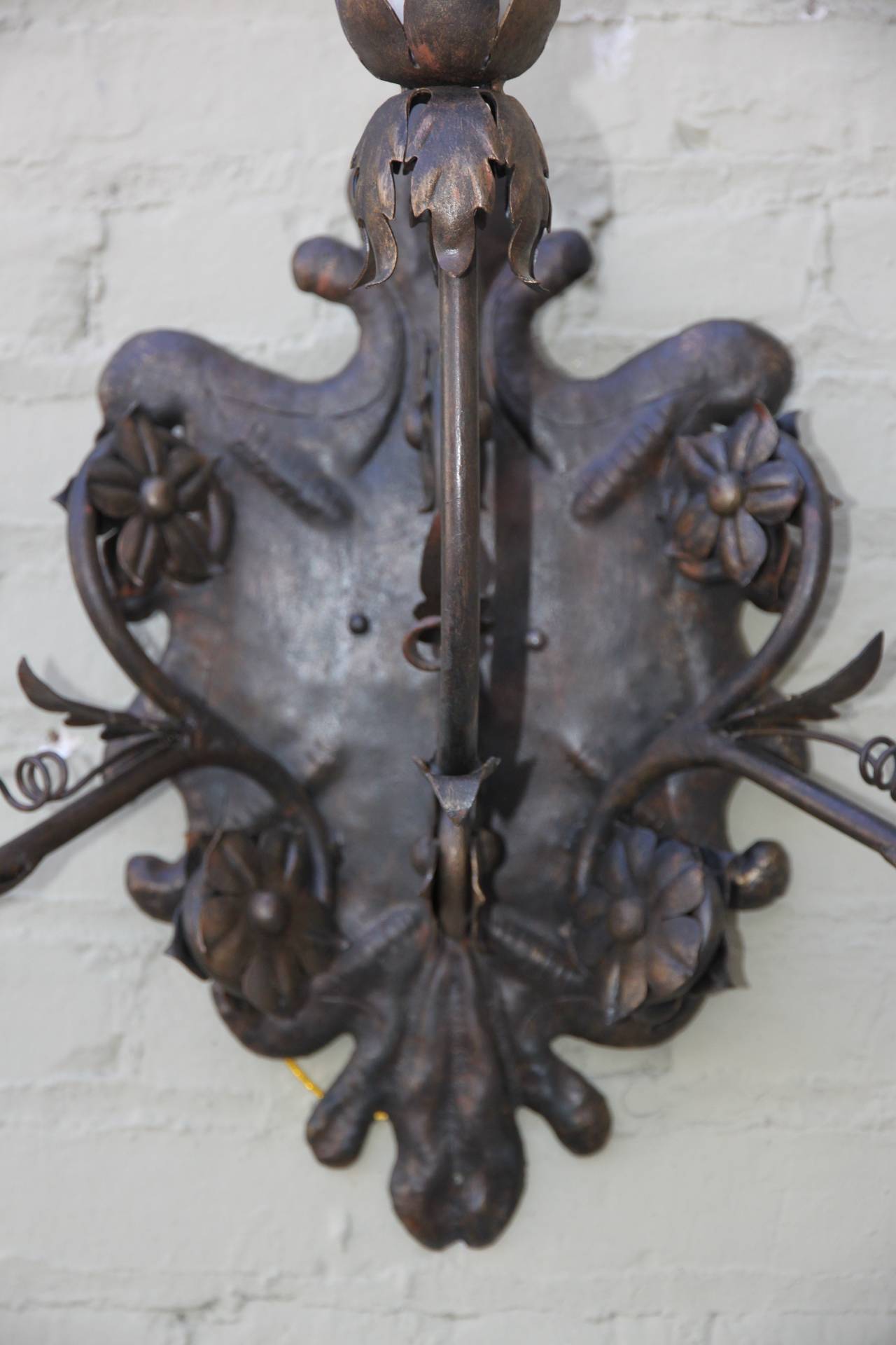 Set of four three-arm Spanish style wrought iron sconces that have been newly wired with wax candle covers.