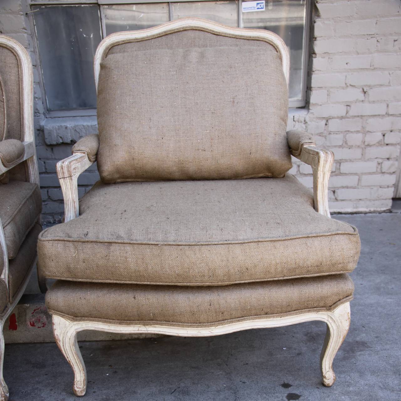 Pair of painted Louis XV style bergere newly upholstered in burlap textile with loose seat and back cushions.