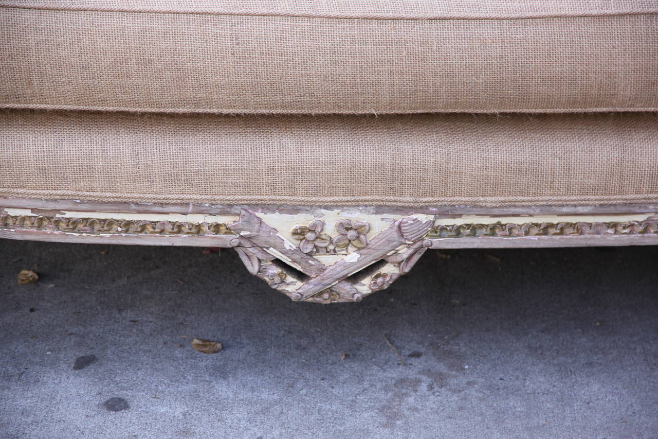 Louis XVI style French carved painted settee standing on four straight fluted legs. Finely carved details throughout. Newly upholstered in burlap textile with original nailhead trim detail. Loose foam cushion.
