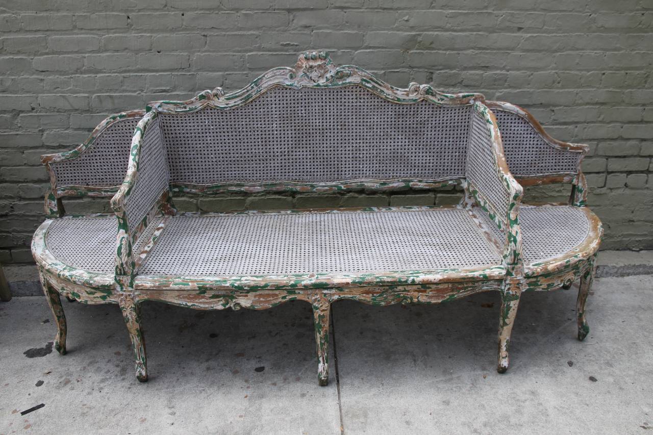French, circa 1930s beautifully painted and caned three section sofa.  The sofa stands on eight cabriole legs that end in rams head feet. The paint is 
