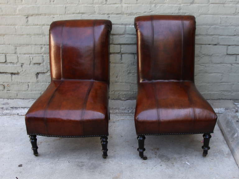 Pair of vintage distressed leather Ralph Lauren sidechairs standing on four legs with casteres with baseball stitching.