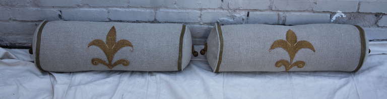 Pair of custom Belgium linen Fleur de lis appliqued bolster pillows with metallic tassels on the ends. Down filled.
