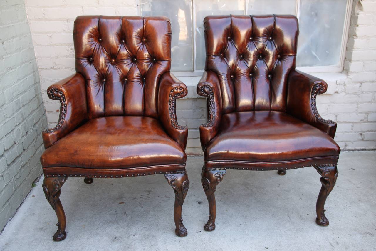 English leather tufted Queen Anne style armchairs with nail head trim detail.