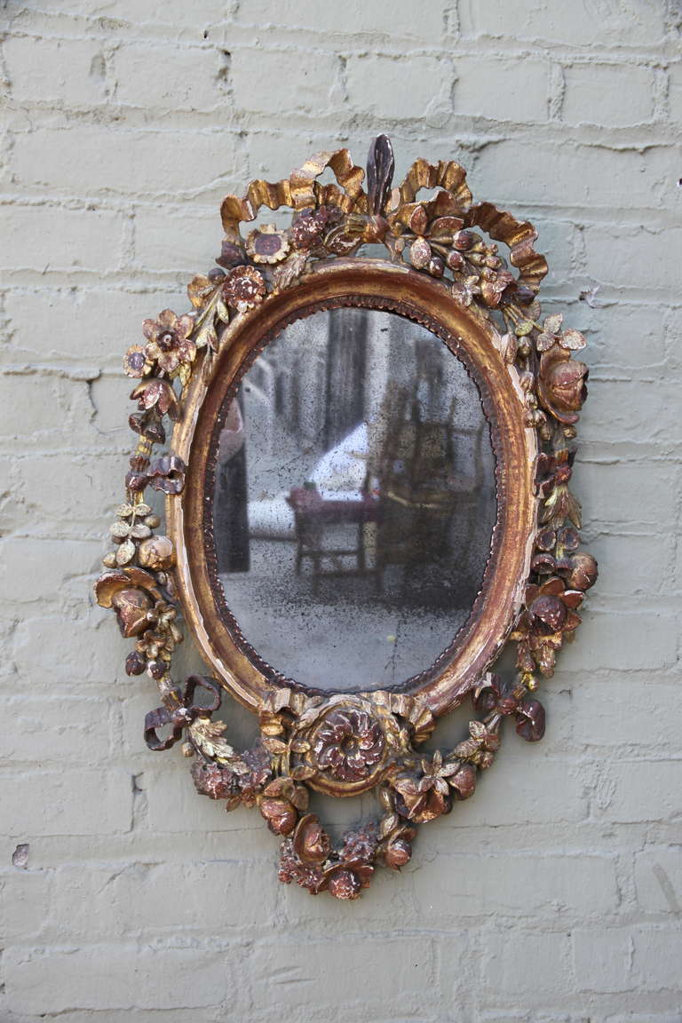 19th century French carved gilt wood mirror with bows and floral design. Antique mirror.