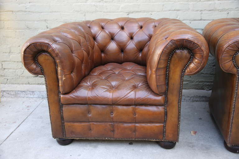 Pair of vintage leather tufted Chesterfield style armchairs with bun feet and nailhead trim detail.