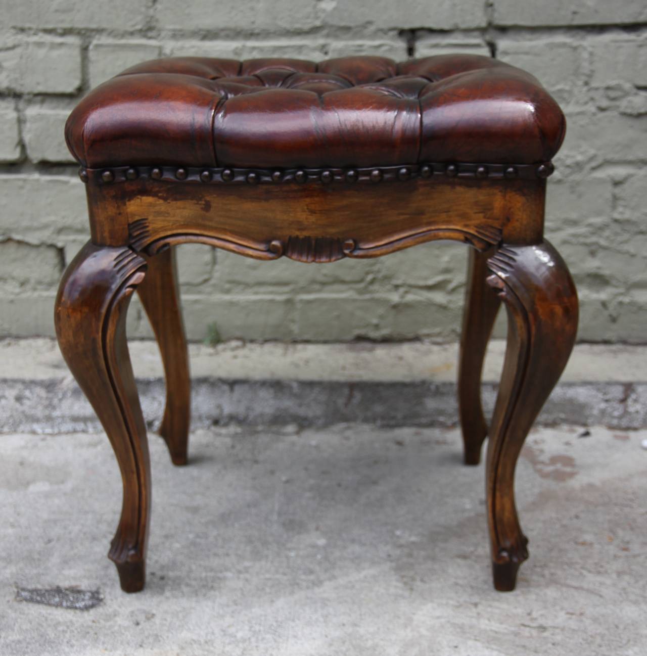 French leather tufted walnut benche standing on four cabriole legs with nailhead trim detail.
