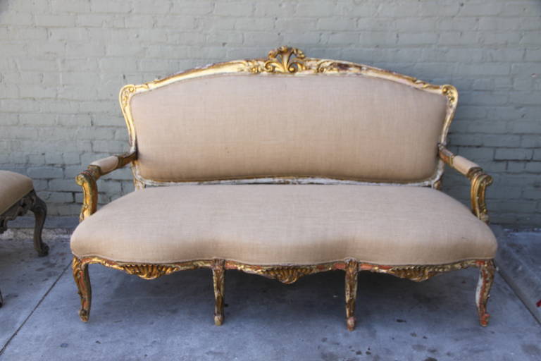 19th century carved French painted and parcel gilt settee standing on eight cabriole legs and newly upholstered in burlap textile with self cording.