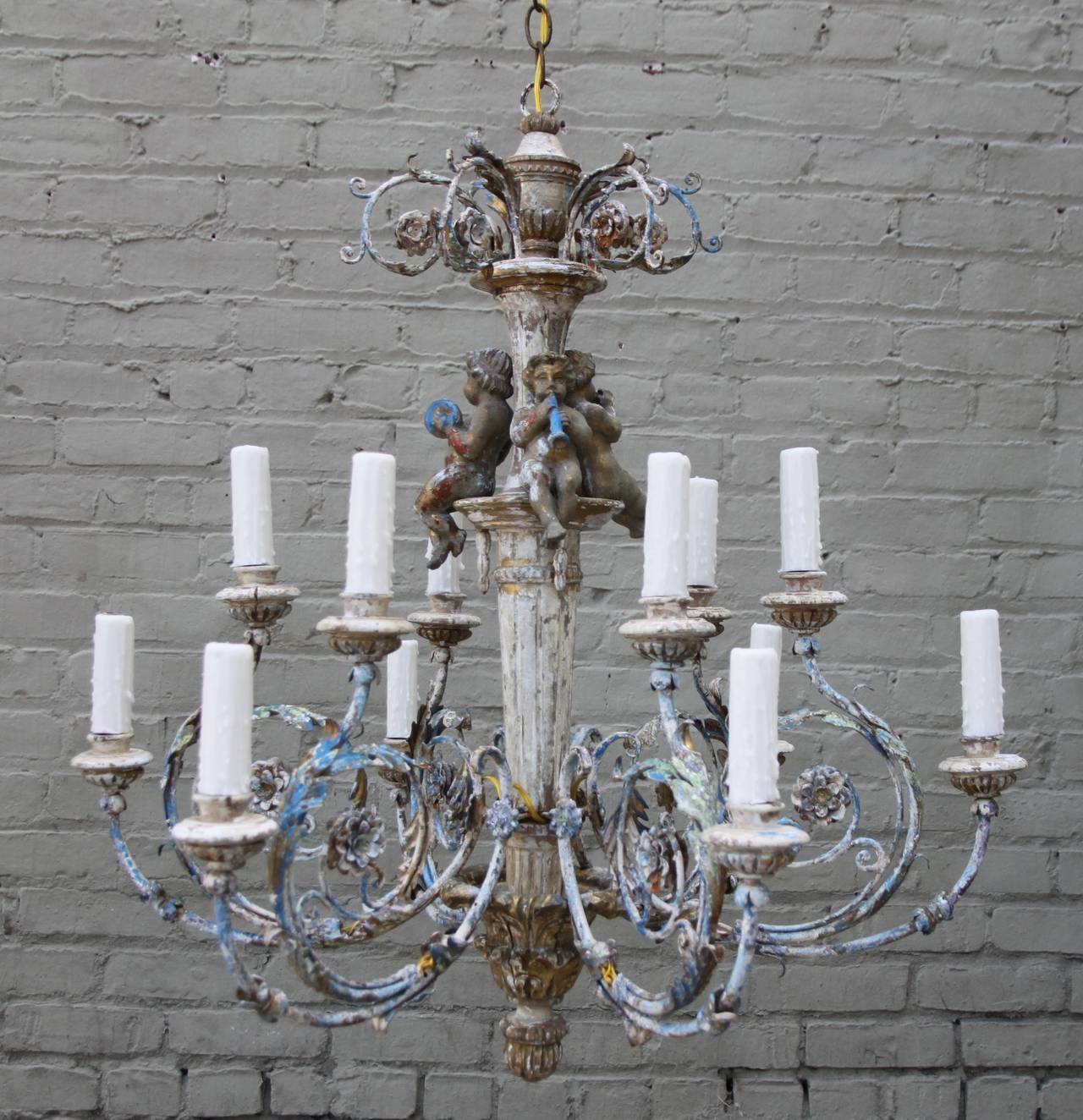 Charming twelve-light iron and wood painted chandelier depicting three cherubs playing musical instruments. The fixture has been newly wired with chain and canopy and is ready to install.