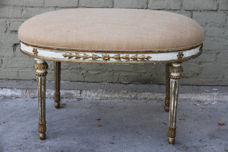 Italian neoclassical style painted and parcel-gilt stool standing on four straight fluted legs and newly upholstered in burlap textile with self welt.